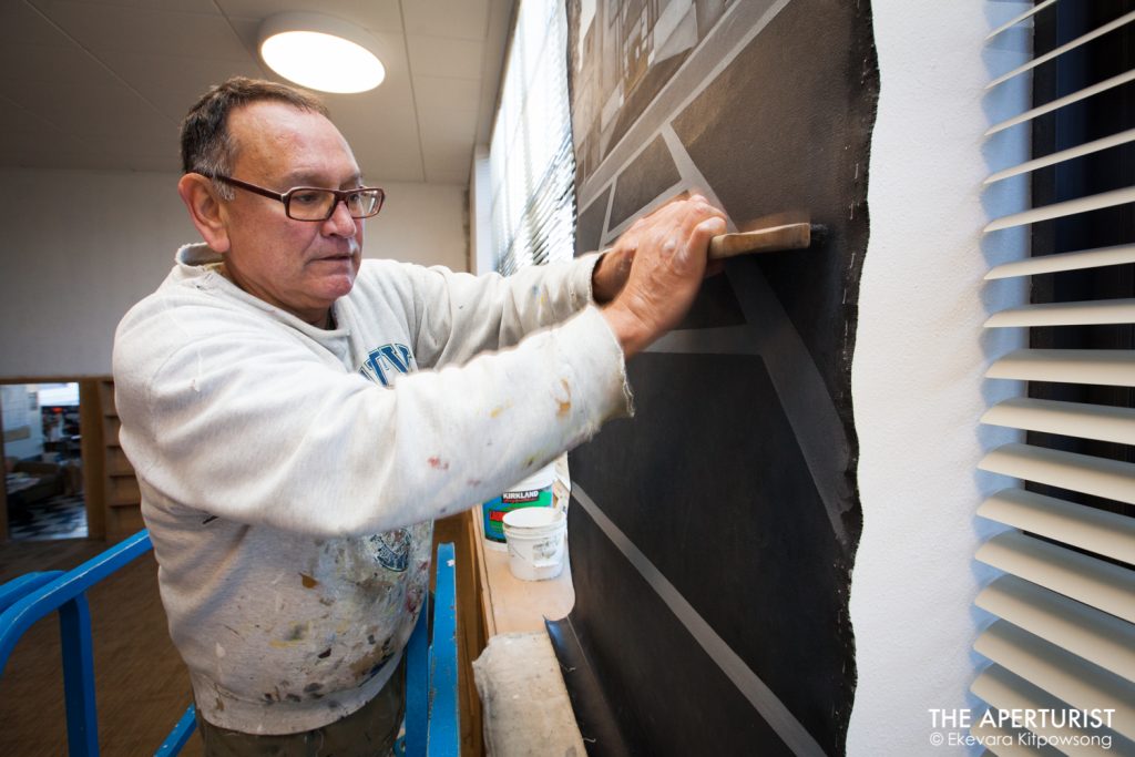  Oakland muralist Daniel Galvez installs one of the canvases which is a part of his new mural "Mack Town Rising" on a wall in The McClymonds Library Innovation Technology Center at McClymonds High School in Oakland, Calif. on Thursday, Dec. 27, 2018. A painting of Stanford University’s Hoover Tower in black & white with blue sky can be seen on the canvas. (Photo by Ekevara Kitpowsong/Current SF)