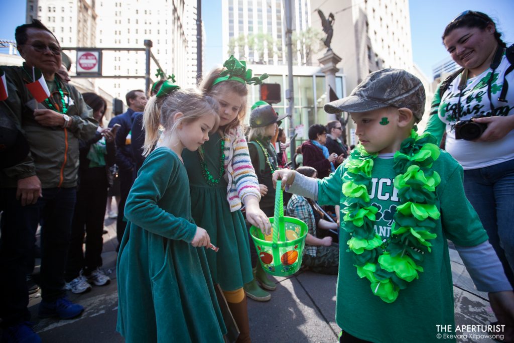 A boy hands out candies in a bucket to two girls on Market Street during the 168th annual San Francisco St. Patrick’s Day Parade on Saturday, March 16, 2019, in San Francisco, Calif. (Photo by Ekevara Kitpowsong/Current SF)