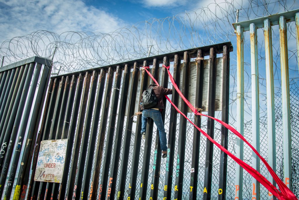 Juan Manuel Barragan Corona, distraught and intoxicated after being recently deported, descends the U.S./Mexico border wall after tying red ribbons on the beams of the border wall as a way to cope with the separation from his children, who remain in the U.S., Sunday, March 10, 2019. (Photo by Mabel Jiménez)
