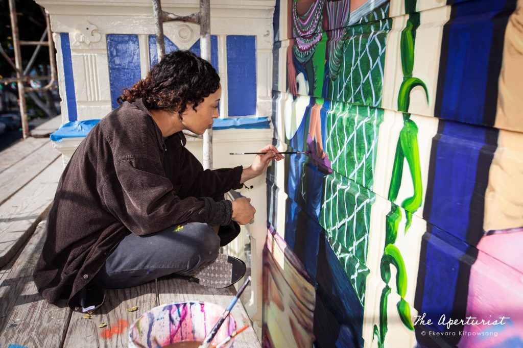 A muralist Adrianna Adams works on the Justice4Amilcar mural, Alto al Fuego en La Misón, on 24th and Capp streets in the Mission District, San Francisco on Saturday, Nov. 9, 2019. (Photo by Ekevara Kitpowsong/Current SF)