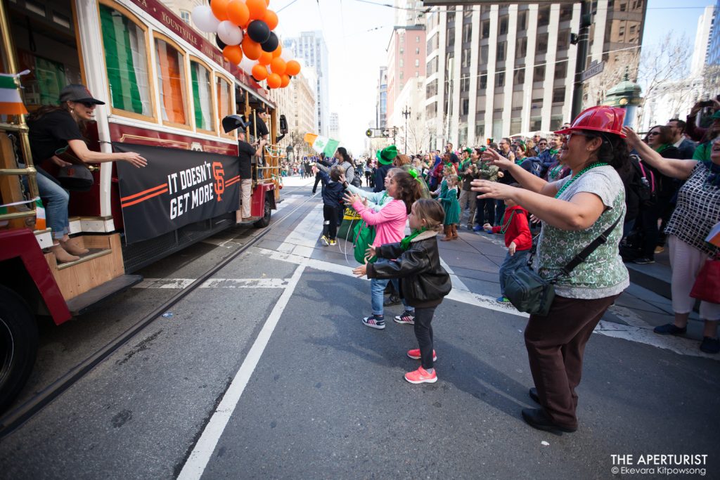 Participants in a cable car throw hats and backpacks to the crowd on Market Street during the 168th annual San Francisco St. Patrick’s Day Parade on Saturday, March 16, 2019, in San Francisco, Calif. (Photo by Ekevara Kitpowsong/Current SF)