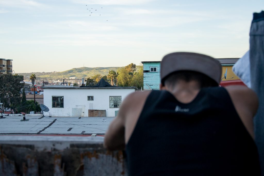 Jenri Jose Juarez Villegas, a 16-year-old refugee from El Salvador, notices a patch of green U.S. soil visible amongst the Tijuana skyline from the backyard of Jardín de las Mariposas, an LGBT drug and alcohol recovery center that recently started opening its doors to LGBT refugees, March 15, 2019. Juarez fled El Salvador after gangs kidnapped his younger sister and threatened his parents. After paying a ransom, his sister was returned, heavily bruised. All his family members fled separately and he does not know any of their whereabouts, or whether they are alive. (Photo by Mabel Jiménez)