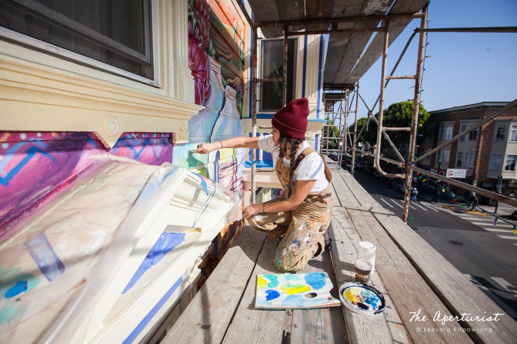 A muralist Flavia Elisa Mora works on the Justice4Amilcar mural, Alto al Fuego en La Misón, on 24th and Capp streets in the Mission District, San Francisco on Saturday, Nov. 9, 2019. (Photo by Ekevara Kitpowsong/Current SF)